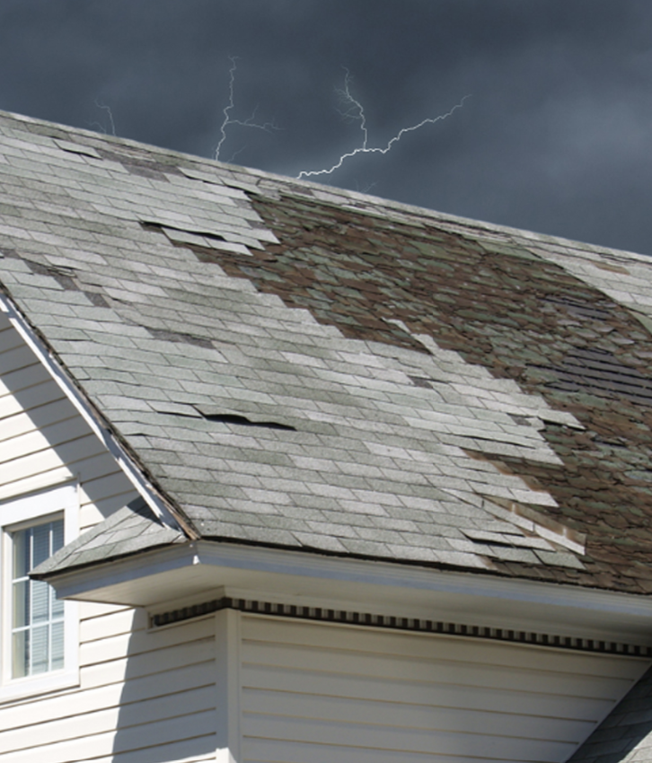 Stormy sky with lightning over a house roof showing missing shingles and wind damage. Short, concise visual of storm-damaged roof.