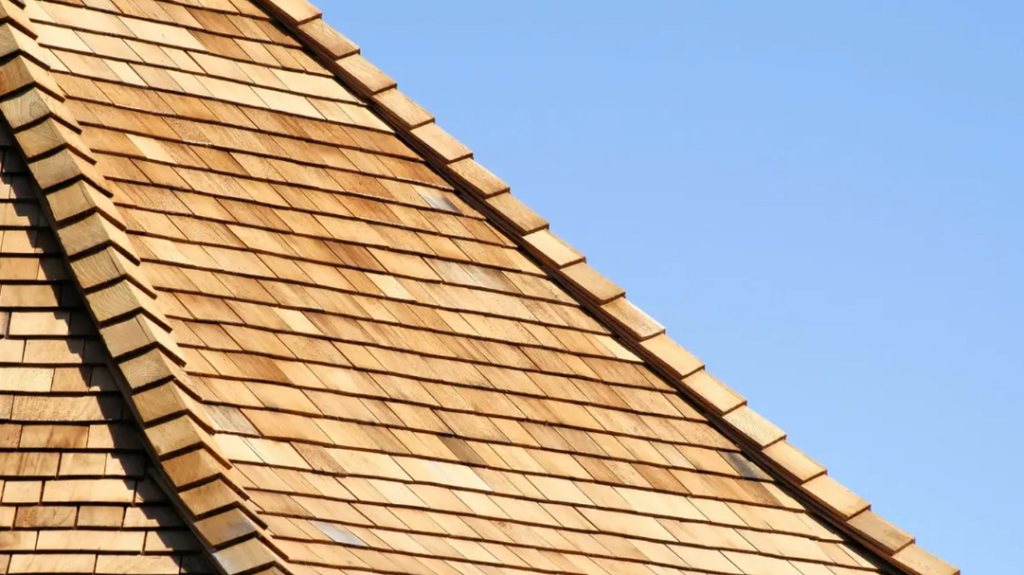 Wooden shingle roof diagonally angled against a clear blue sky, highlighting the warm, natural wood tones and textures.